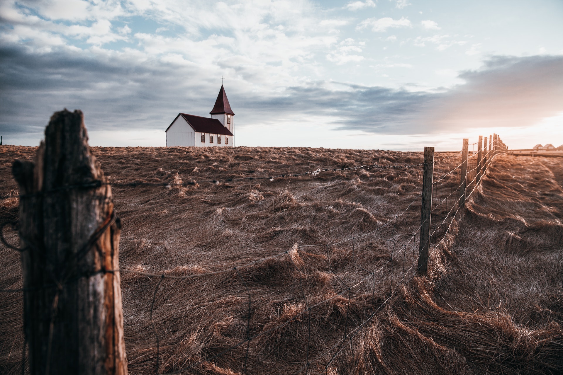 church standing in a field next to barbed wire fence