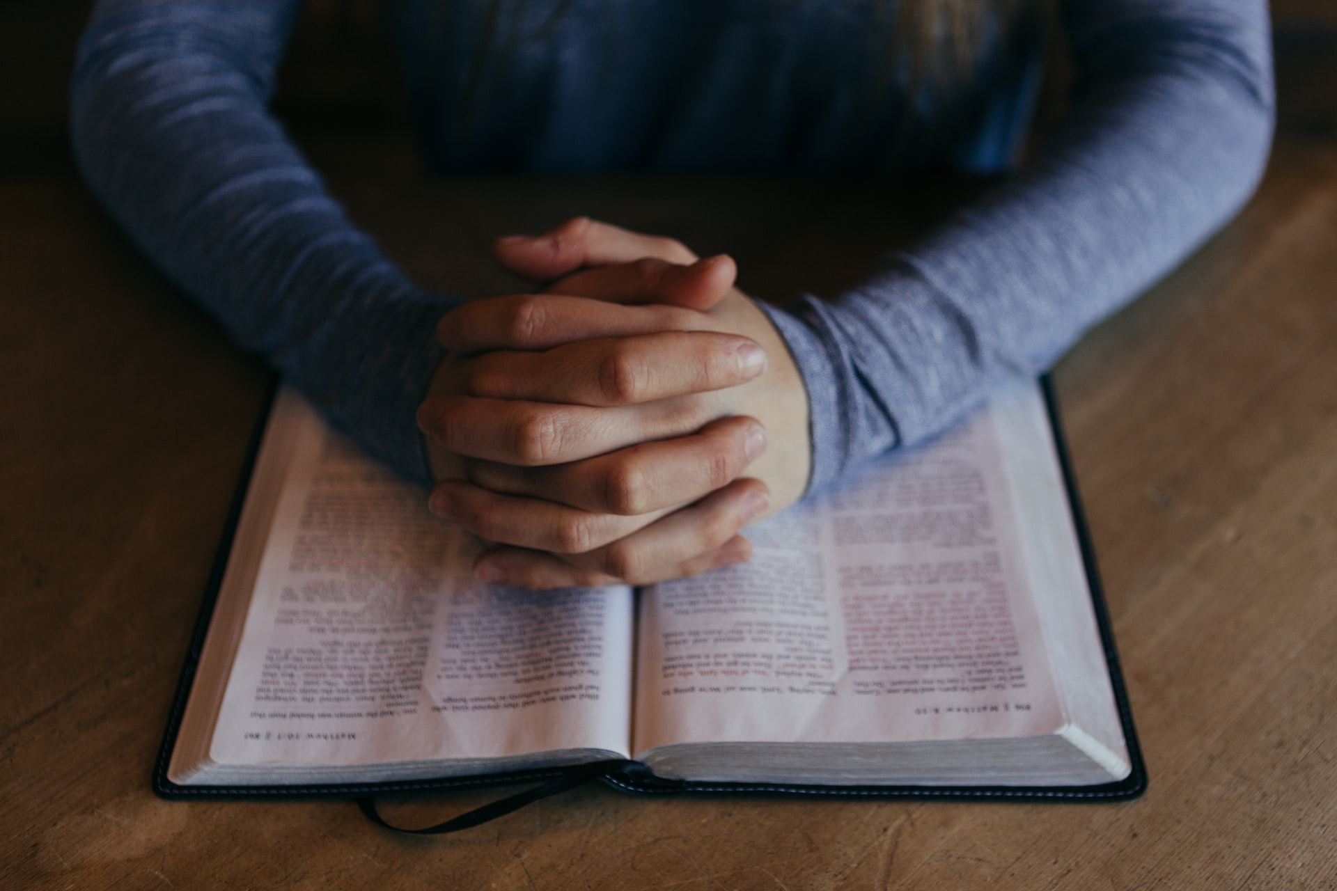 hands clasped over bible on a desk