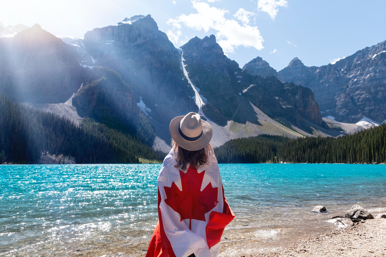 person draped in Canada flat in front of mountains