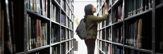 woman in library looking at book shelves